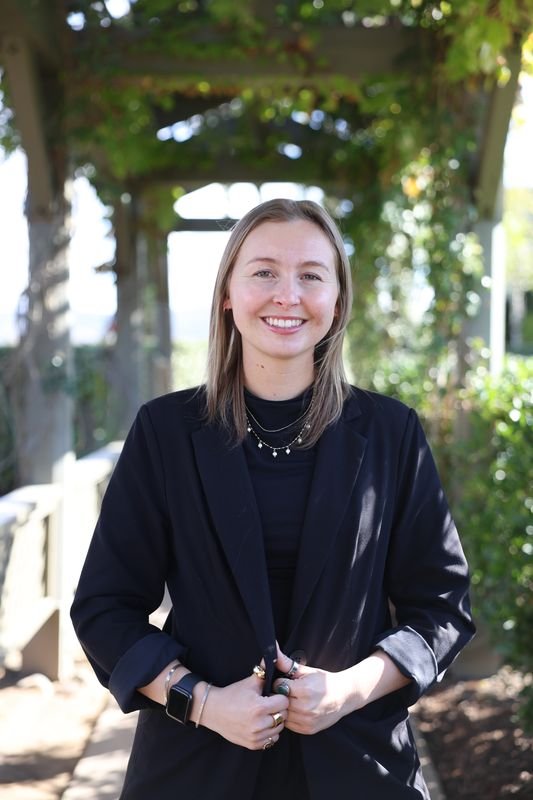 Photo of Mackenzie couch - Assistant hotel manager at Ponte smiling outdoors wearing a black blazer.