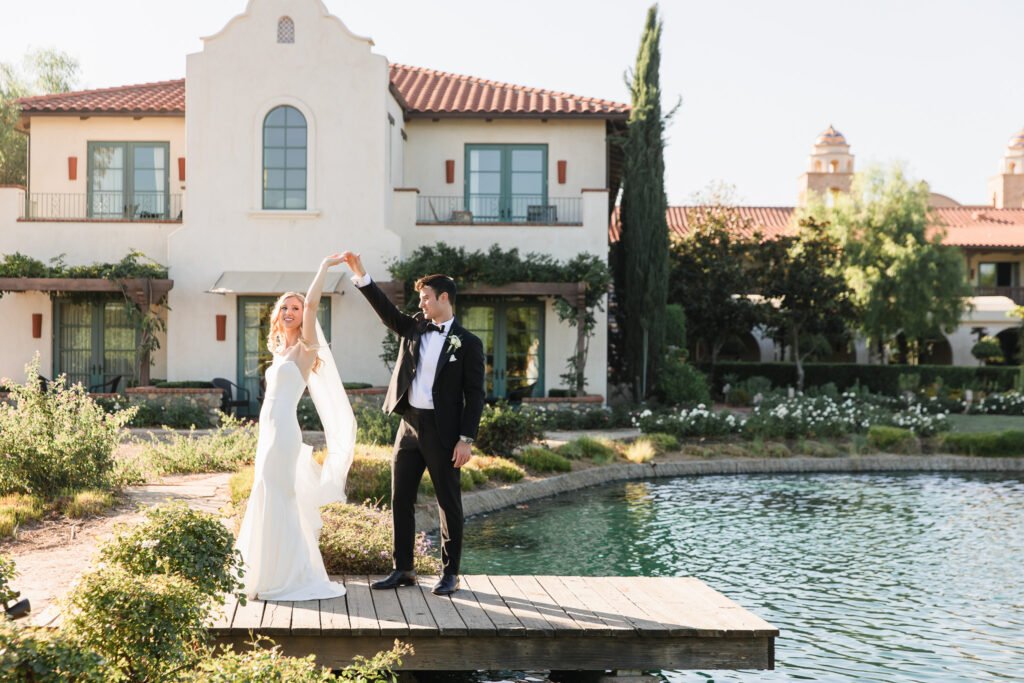 A wedding photo on the pond with a groom twirling his bride.